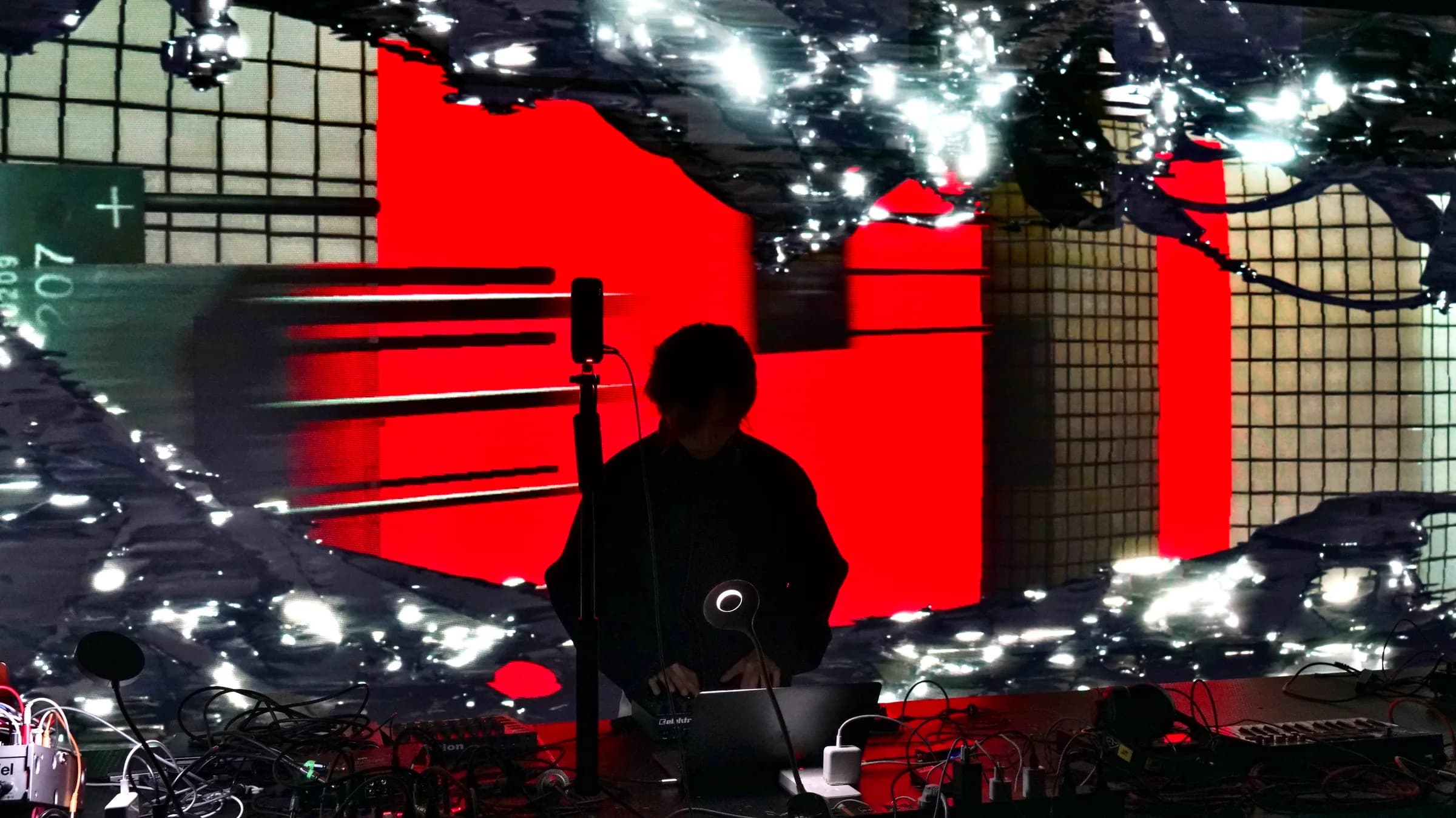 Performers silhouetted against vivid red real-time visuals