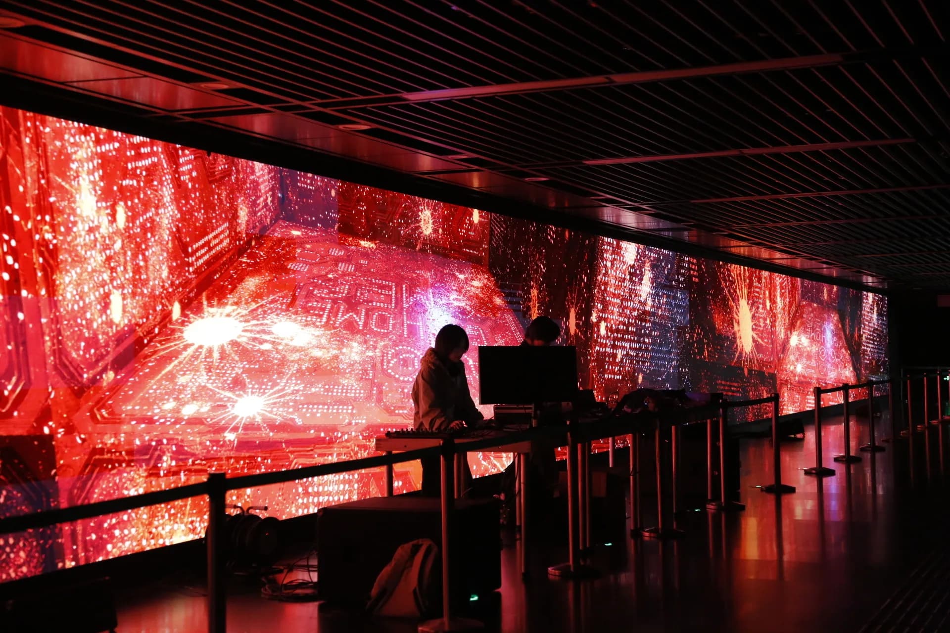 Performers in front of a red circuit-like projected environment